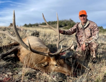 A male hunter posing with his bull elk after the hunt